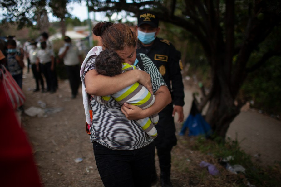 A woman carries her son as Honduran migrants confront Guatemalan soldiers and police manning a roadblock that prevents them from advancing toward the U.S., on the highway in Vado Hondo, Guatemala, on Jan. 18, 2021. (Sandra Sebastian / Associated Press)