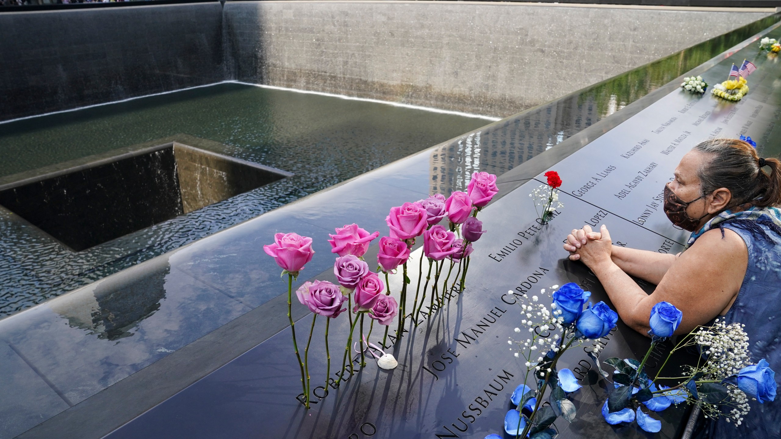 In this Friday Sept. 11, 2020, file photo, a mourner prays over the etched name of the deceased Emilio Pete Ortiz at the National September 11 Memorial and Museum in New York. Authorities say a U.S. Army soldier has been arrested in Georgia on terrorism charges after he spoke online about plotting to blow up the 9/11 Memorial in New York City and attack U.S. soldiers in the Middle East. (AP Photo/John Minchillo, File)