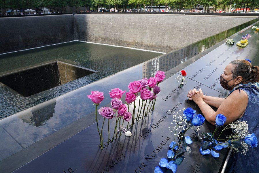 In this Friday Sept. 11, 2020, file photo, a mourner prays over the etched name of the deceased Emilio Pete Ortiz at the National September 11 Memorial and Museum in New York. Authorities say a U.S. Army soldier has been arrested in Georgia on terrorism charges after he spoke online about plotting to blow up the 9/11 Memorial in New York City and attack U.S. soldiers in the Middle East. (AP Photo/John Minchillo, File)