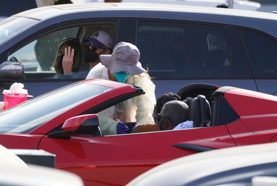 A woman is vaccinated inside a convertible vehicle at a mass COVID-19 vaccination site outside The Forum in Inglewood on Jan. 19, 2021. (Damian Dovarganes / Associated Press)