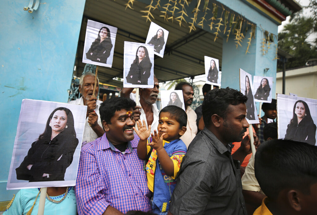 A child reacts as villagers hold placards featuring U.S. Vice President-elect Kamala Harris after participating in special prayers ahead of her inauguration, outside a Hindu temple in Thulasendrapuram, the hometown of Harris' maternal grandfather, south of Chennai, Tamil Nadu state, India on Jan. 20, 2021. (AP Photo/Aijaz Rahi)