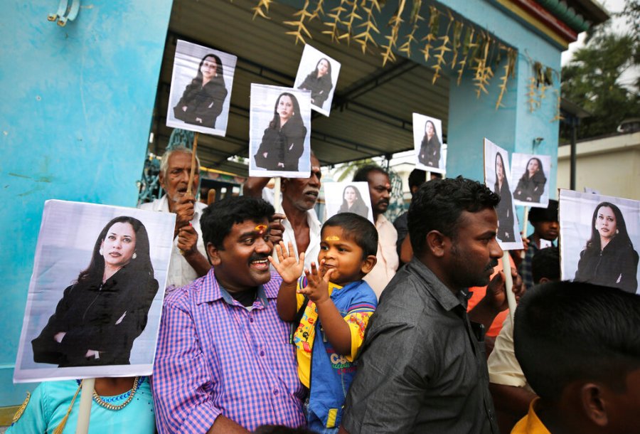 A child reacts as villagers hold placards featuring U.S. Vice President-elect Kamala Harris after participating in special prayers ahead of her inauguration, outside a Hindu temple in Thulasendrapuram, the hometown of Harris' maternal grandfather, south of Chennai, Tamil Nadu state, India on Jan. 20, 2021. (AP Photo/Aijaz Rahi)