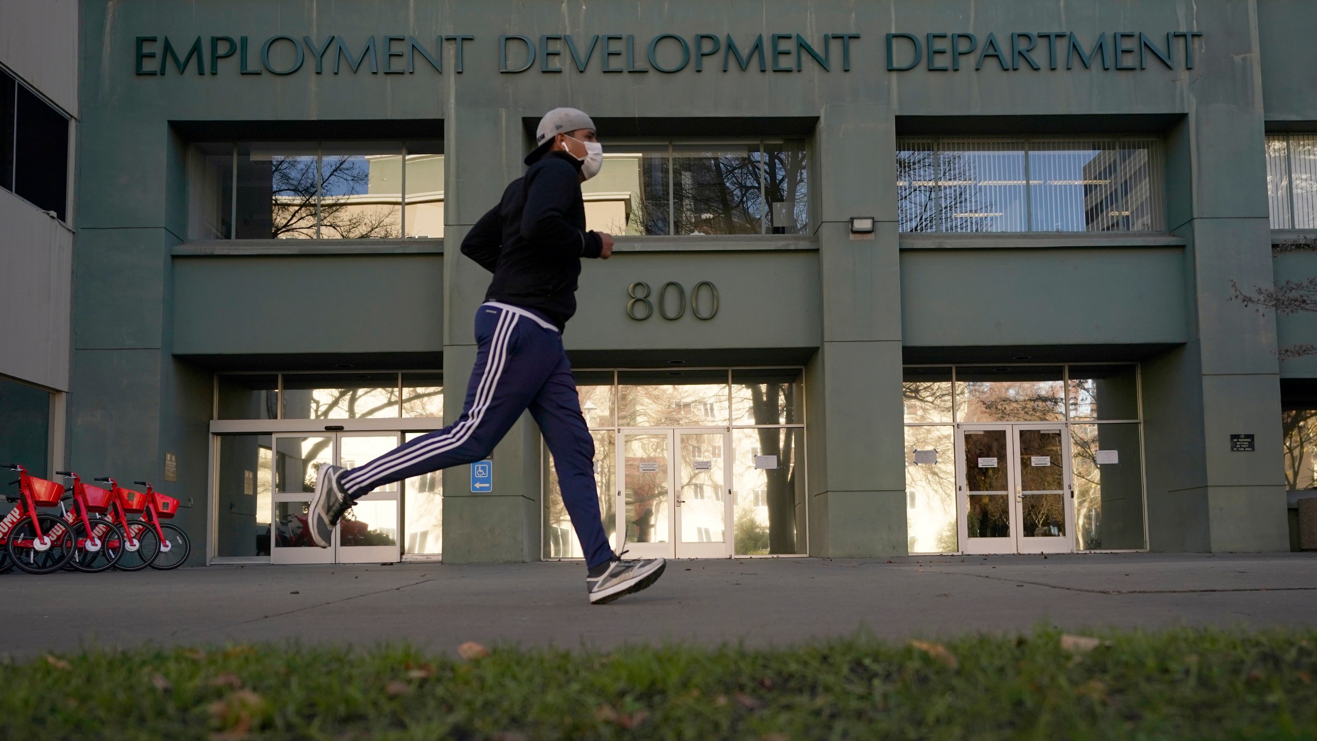 In this Dec. 18, 2020 file photo a runner passes the office of the California Employment Development Department in Sacramento, Calif. (AP Photo/Rich Pedroncelli)