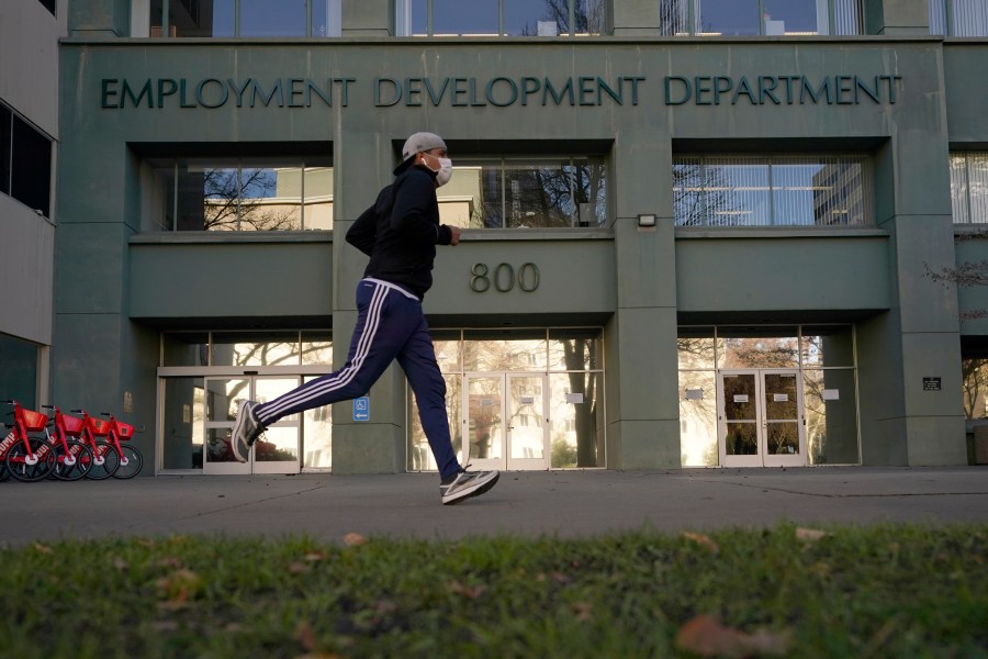 In this Dec. 18, 2020 file photo a runner passes the office of the California Employment Development Department in Sacramento, Calif. (AP Photo/Rich Pedroncelli)