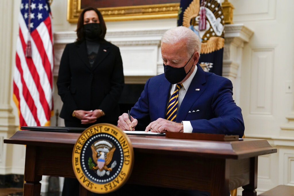 President Joe Biden signs executive orders on the economy in the State Dining Room of the White House, Friday, Jan. 22, 2021, in Washington. (AP Photo/Evan Vucci)