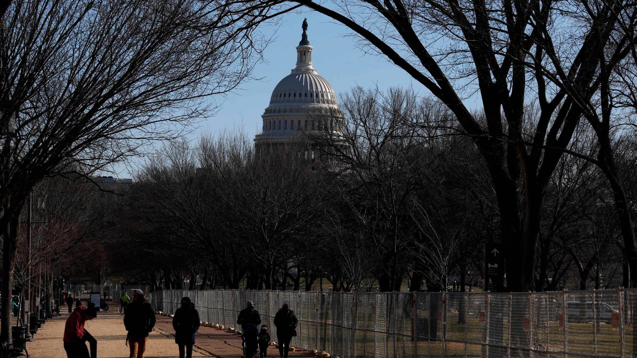 People stroll past a section of the National Mall by the Capitol where workers were still dismantling inauguration installations, after most downtown streets and public spaces had reopened to the public, on Saturday, Jan. 23, 2021 in Washington. (AP Photo/Rebecca Blackwell)