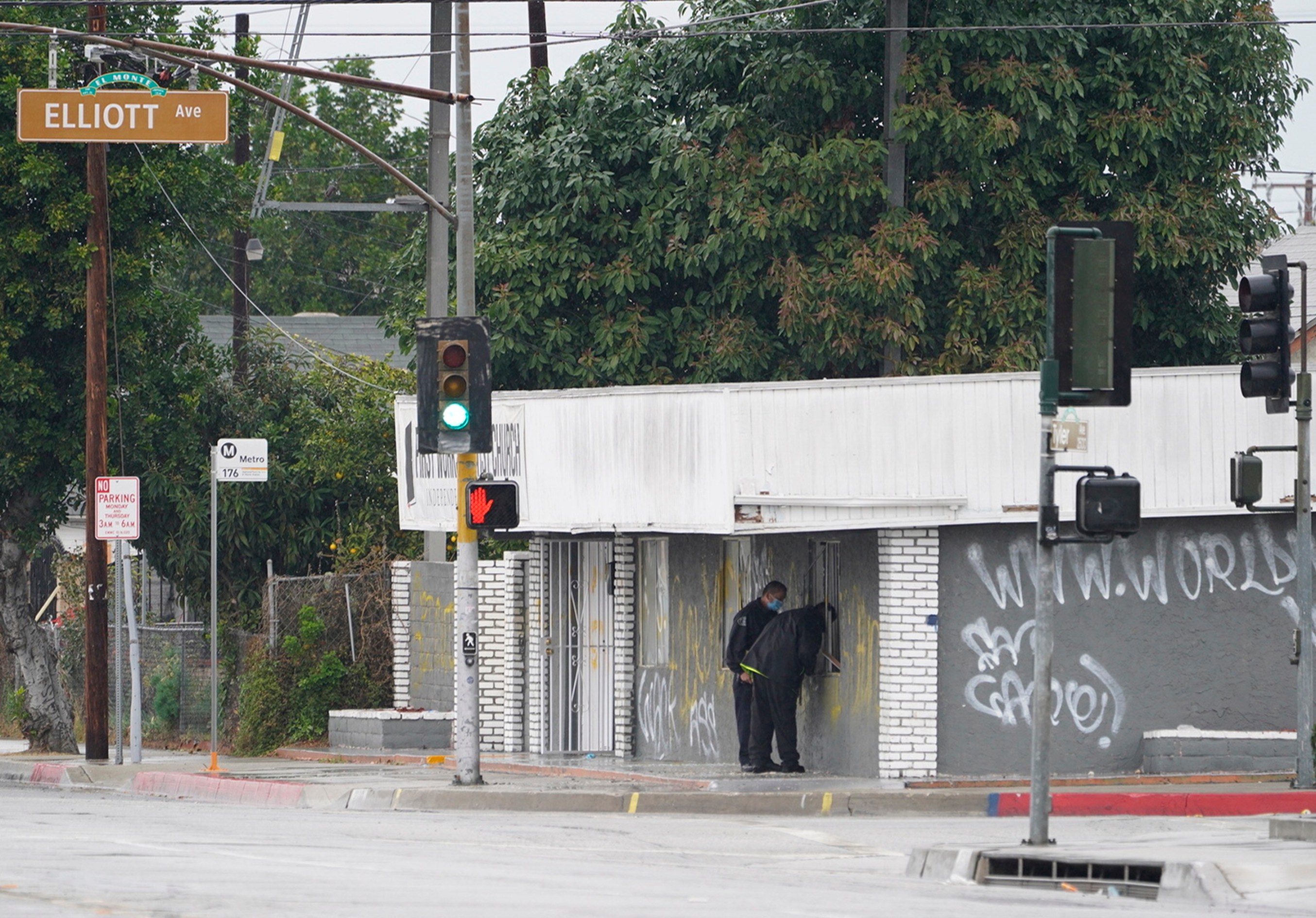 El Monte Police Chief David Reynoso, left, with another officer peeks inside the church's windows after an explosion in El Monte, Calif., Saturday, Jan. 23, 2021. (AP Photo/Damian Dovarganes)