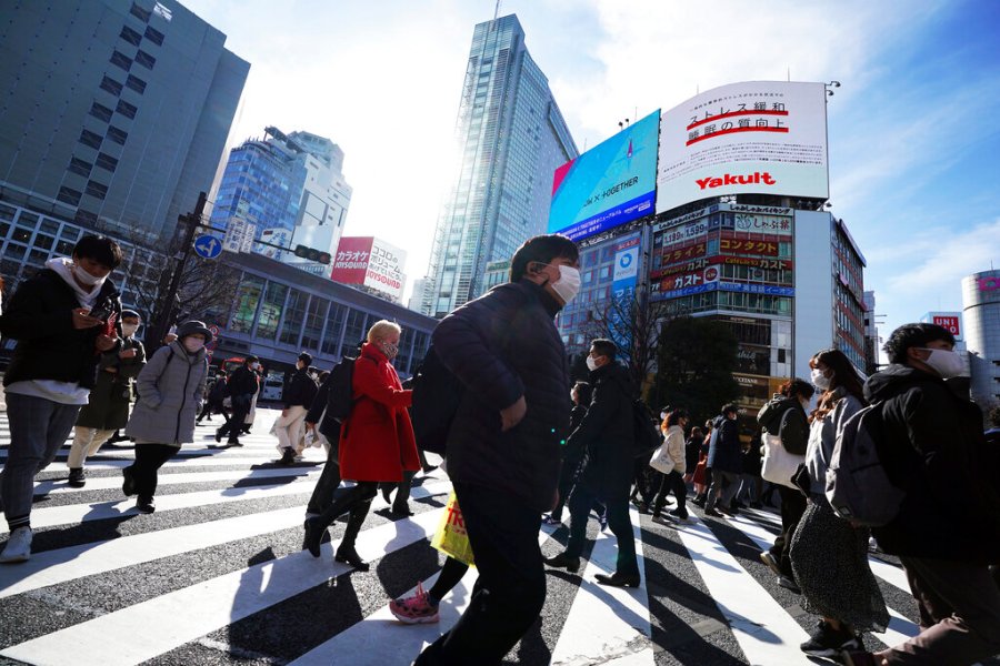 People wearing protective masks to help curb the spread of the coronavirus walk along pedestrian crossings Monday, Jan. 25, 2021 in Tokyo. (AP Photo/Eugene Hoshiko)