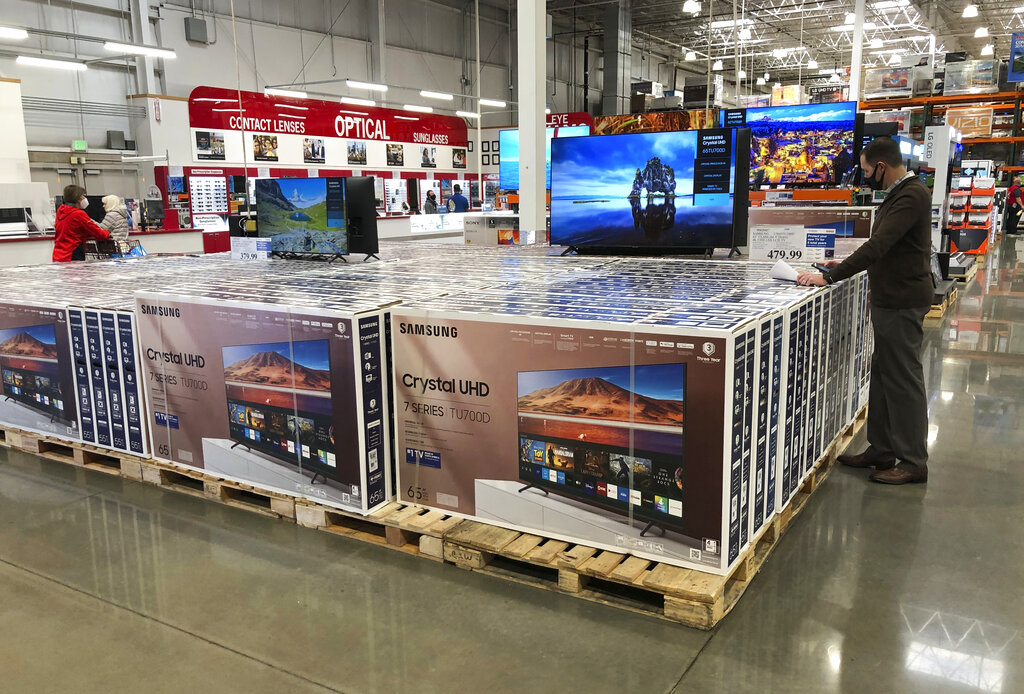 In this Nov. 10, 2020 photo, a shopper stands by a display of Samsung 65-inch televisions in a Costco warehouse in Sheridan, Colo. (AP Photo/David Zalubowski)