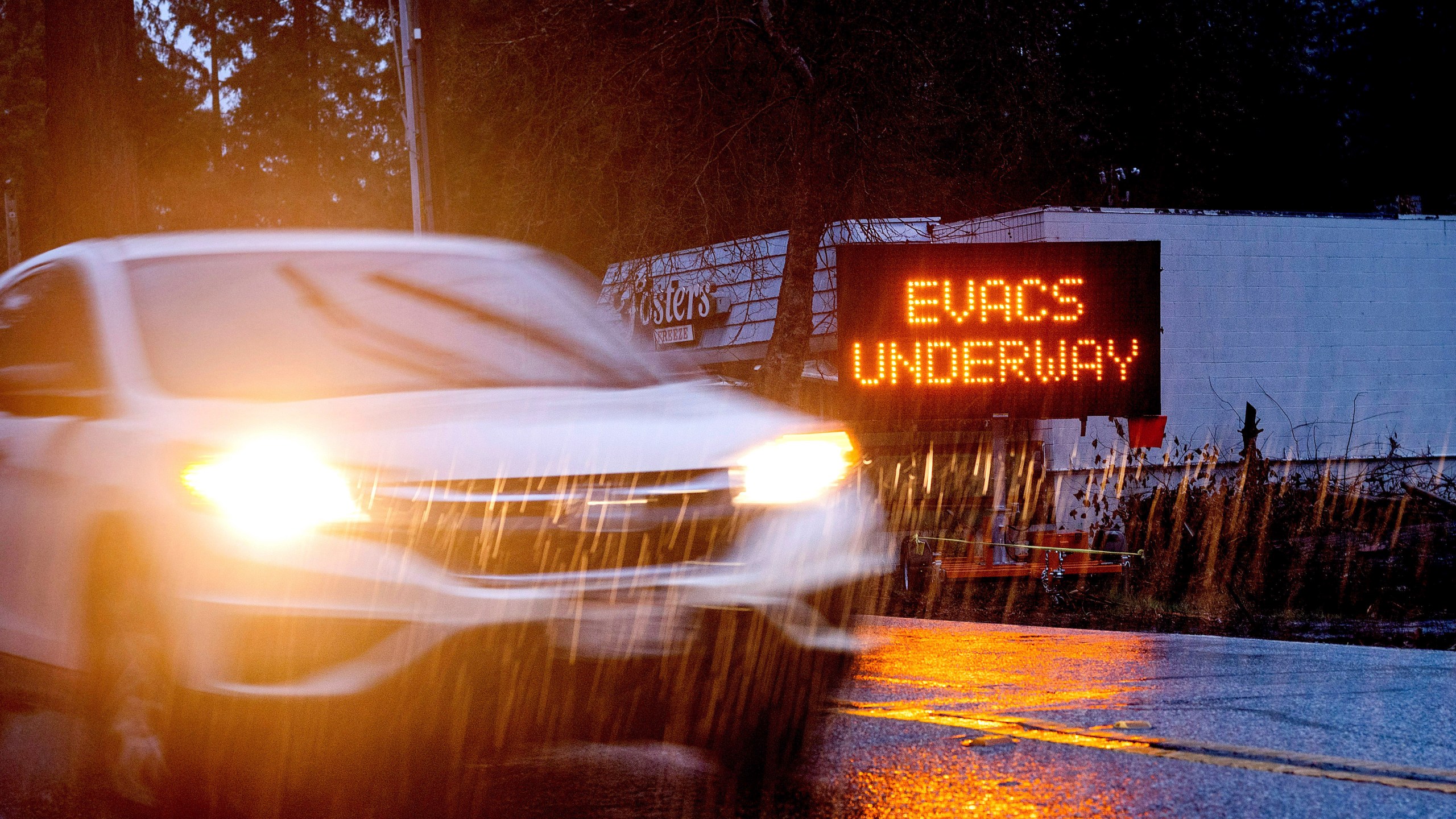 A car passes an evacuation warning in the Boulder Creek community, which burned during last summer's CZU Lightning Complex Fire, in Santa Cruz County, Calif., on Tuesday, Jan. 26, 2021. Residents of the Santa Cruz Mountains are under evacuation warnings as heavy rains threaten to cause mudslides in areas scorched during last summer's wildfires. (AP Photo/Noah Berger)