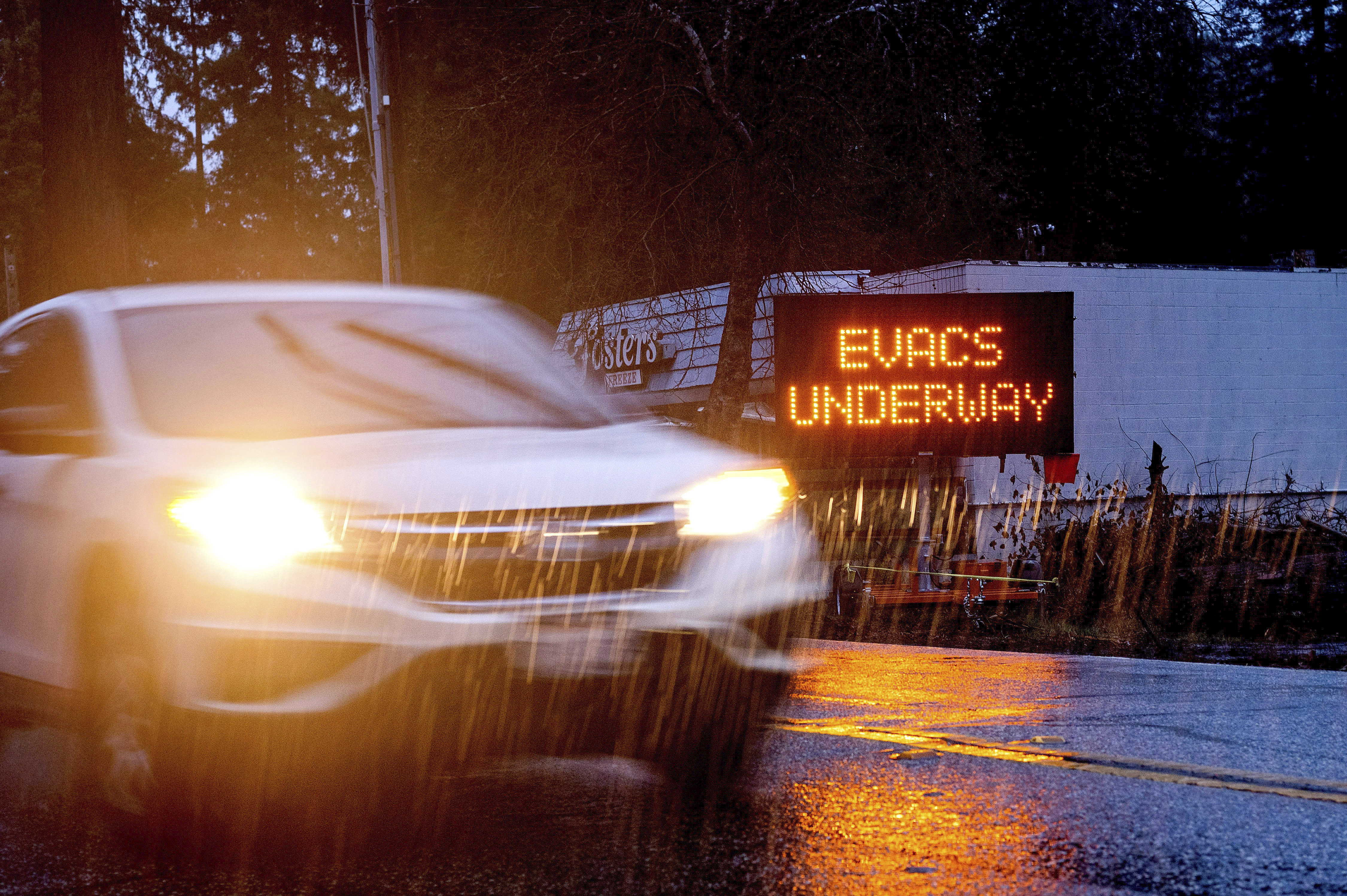 A car passes an evacuation warning in the Boulder Creek community, which burned during last summer's CZU Lightning Complex Fire, in Santa Cruz County, Calif., on Tuesday, Jan. 26, 2021. Residents of the Santa Cruz Mountains are under evacuation warnings as heavy rains threaten to cause mudslides in areas scorched during last summer's wildfires. (AP Photo/Noah Berger)