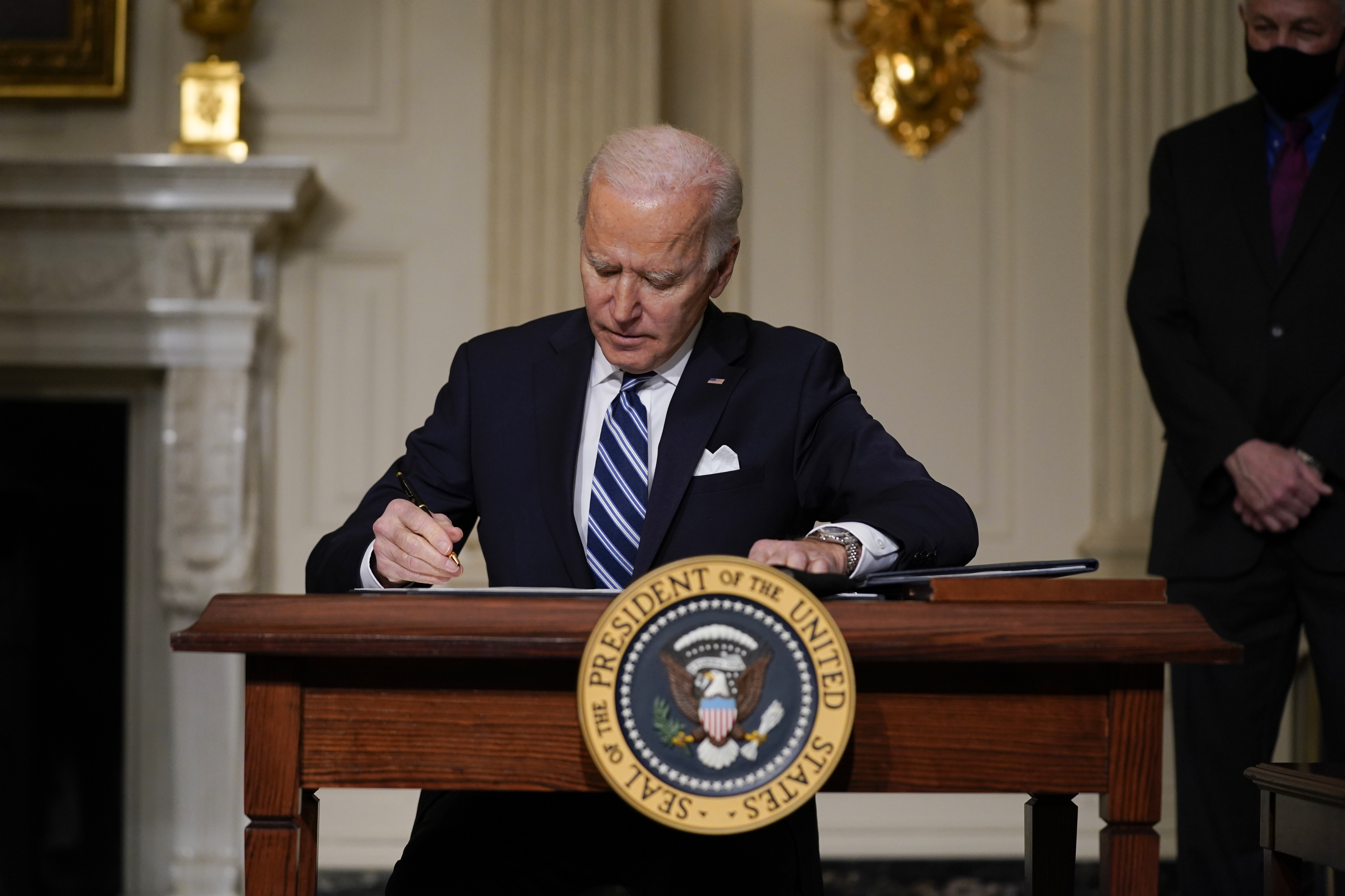 President Joe Biden signs an executive order on climate change in the State Dining Room of the White House on Jan. 27, 2021. (Evan Vucci / Associated Press)