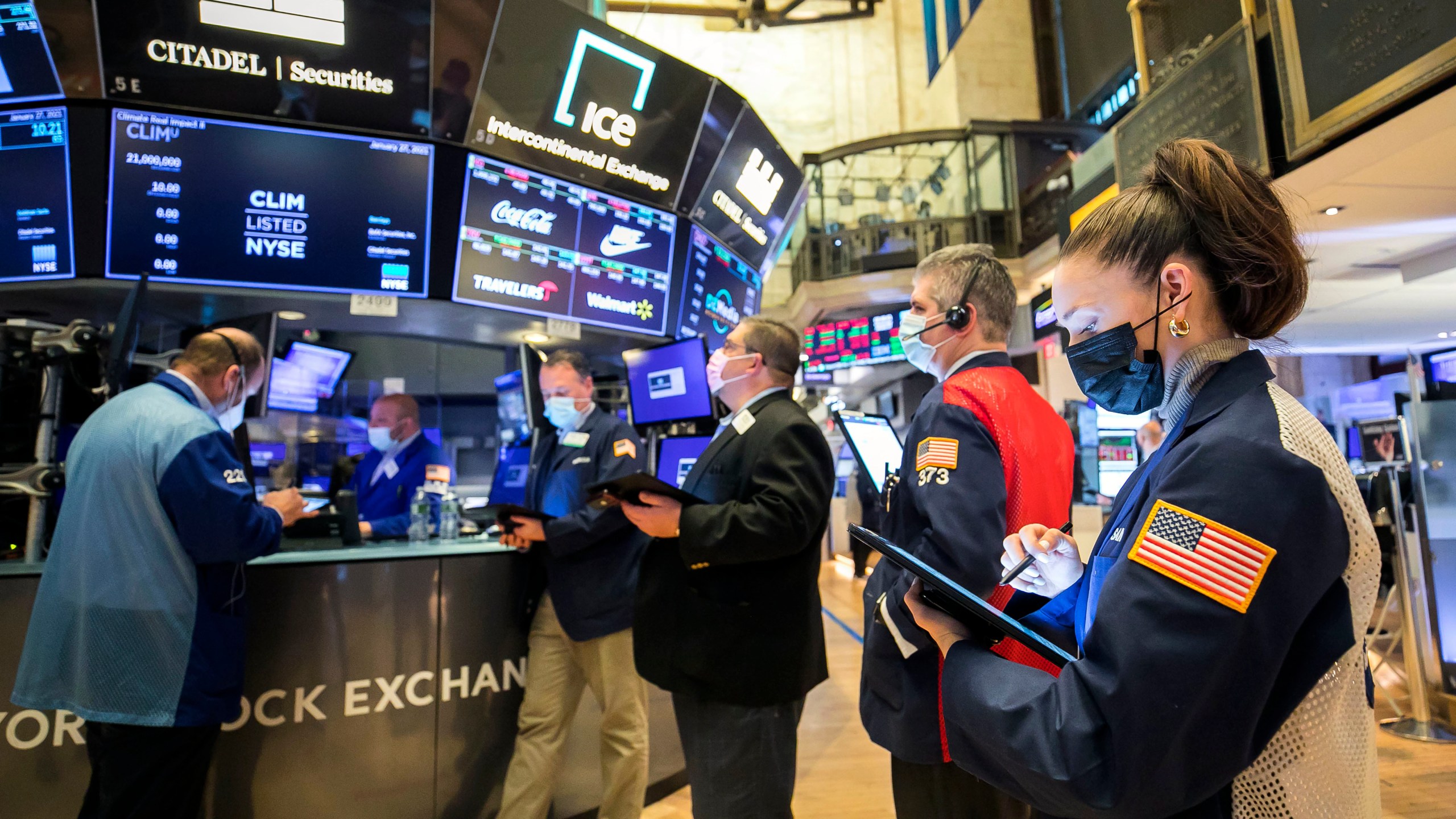 In this photo provided by the New York Stock Exchange, trader Samantha Tavares, right, works with colleagues on the floor, Wednesday, Jan. 27, 2021. Stocks were broadly lower in afternoon trading Wednesday, as investors focus on the outlook for the economy and corporate profits amid a still-raging coronavirus pandemic. (Courtney Crow/New York Stock Exchange via AP)