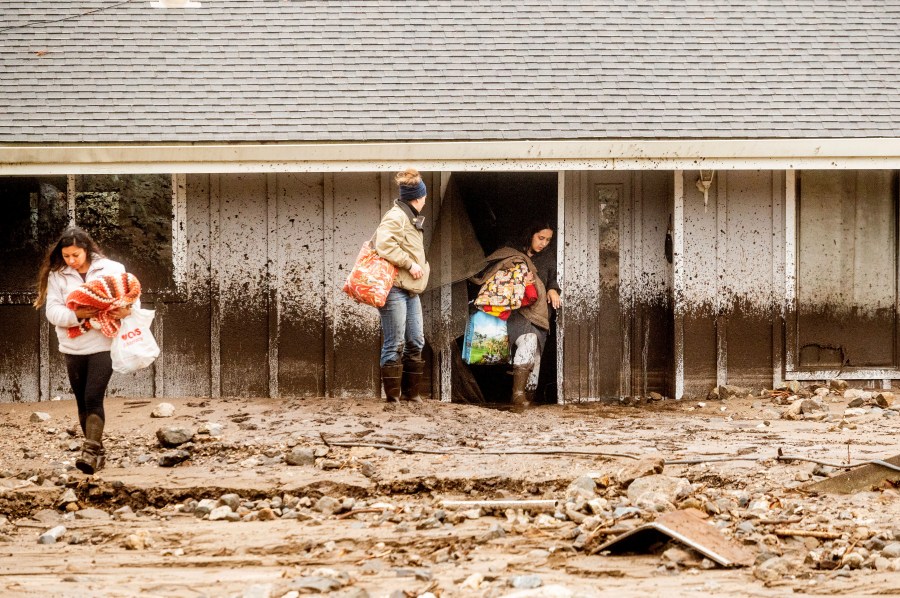 Hana Mohsin, right, carries belongings from a neighbor's home which was damaged in a mudslide on Jan. 27, 2021, in Salinas. (Noah Berger / Associated Press)