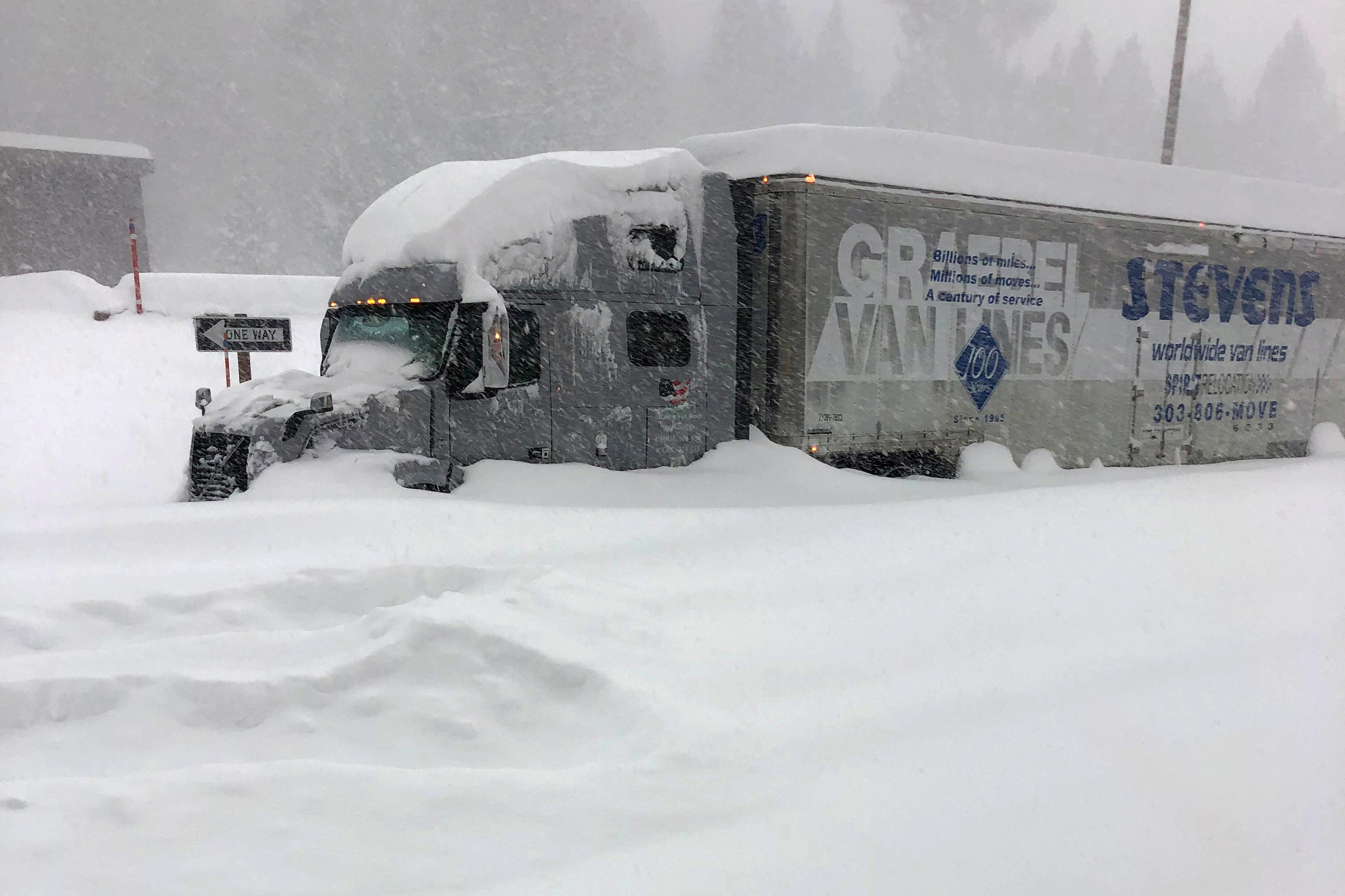 In this photo provided by Caltrans District 9, a tractor trailer that is stuck in heavy snowfall at Crestview along U.S. Hwy 395, closed in Mono County, Calif., on Jan. 27, 2021. (Andy Richard / Caltrans District 9 via Associated Press)