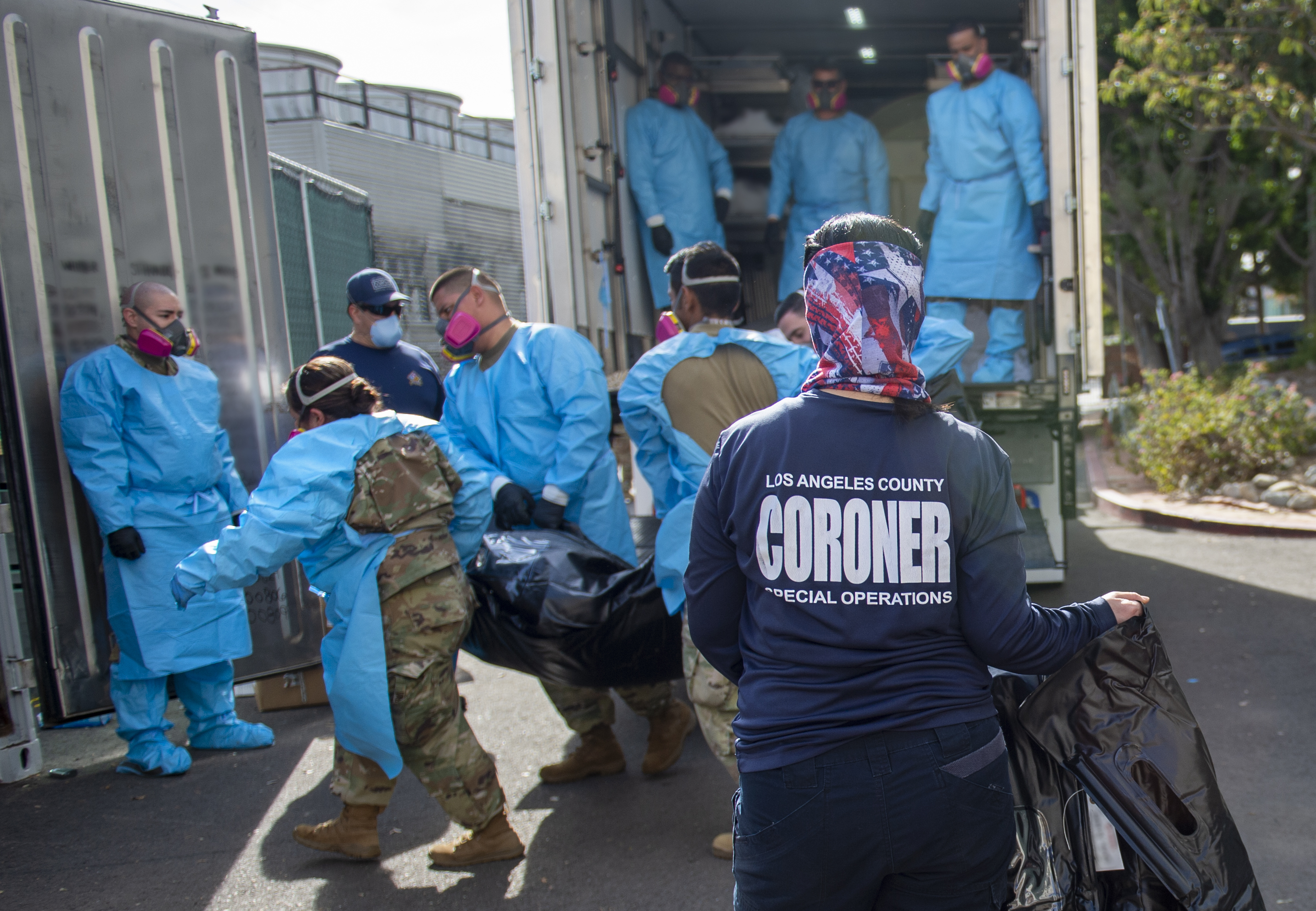 In this Tuesday, Jan. 12, 2021, file photo, provided by the L.A. County Dept. of Medical Examiner-Coroner, Elizabeth "Liz" Napoles, right, works alongside the National Guard who are helping to process COVID-19 deaths that are be placed into temporary storage at L.A. County Medical Examiner-Coroner Office in Los Angeles. (LA County Dept. of Medical Examiner-Coroner via AP, File)