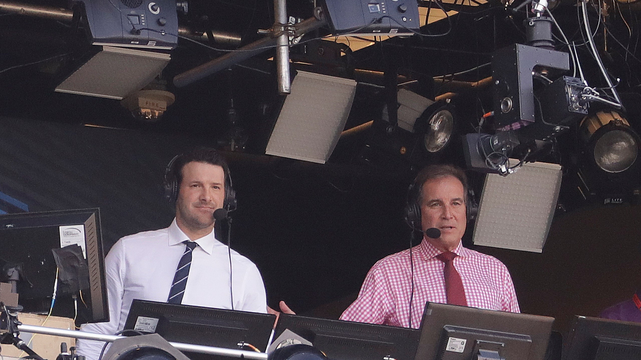 In this Sept. 24, 2017, file photo, Tony Romo and Jim Nantz work in the broadcast booth before an NFL football game between the Green Bay Packers and the Cincinnati Bengals in Green Bay, Wis. Nantz and Romo were inseparable when CBS broadcast the Super Bowl two years ago. Next week, they won't see each other until they are in the broadcast booth a couple hours prior to kickoff. Keeping announcers separated until game day has been standard practice this season due to the Coronavirus pandemic. (AP Photo/Morry Gash, File)