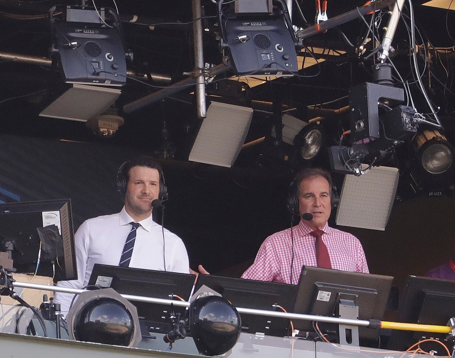 In this Sept. 24, 2017, file photo, Tony Romo and Jim Nantz work in the broadcast booth before an NFL football game between the Green Bay Packers and the Cincinnati Bengals in Green Bay, Wis. Nantz and Romo were inseparable when CBS broadcast the Super Bowl two years ago. Next week, they won't see each other until they are in the broadcast booth a couple hours prior to kickoff. Keeping announcers separated until game day has been standard practice this season due to the Coronavirus pandemic. (AP Photo/Morry Gash, File)