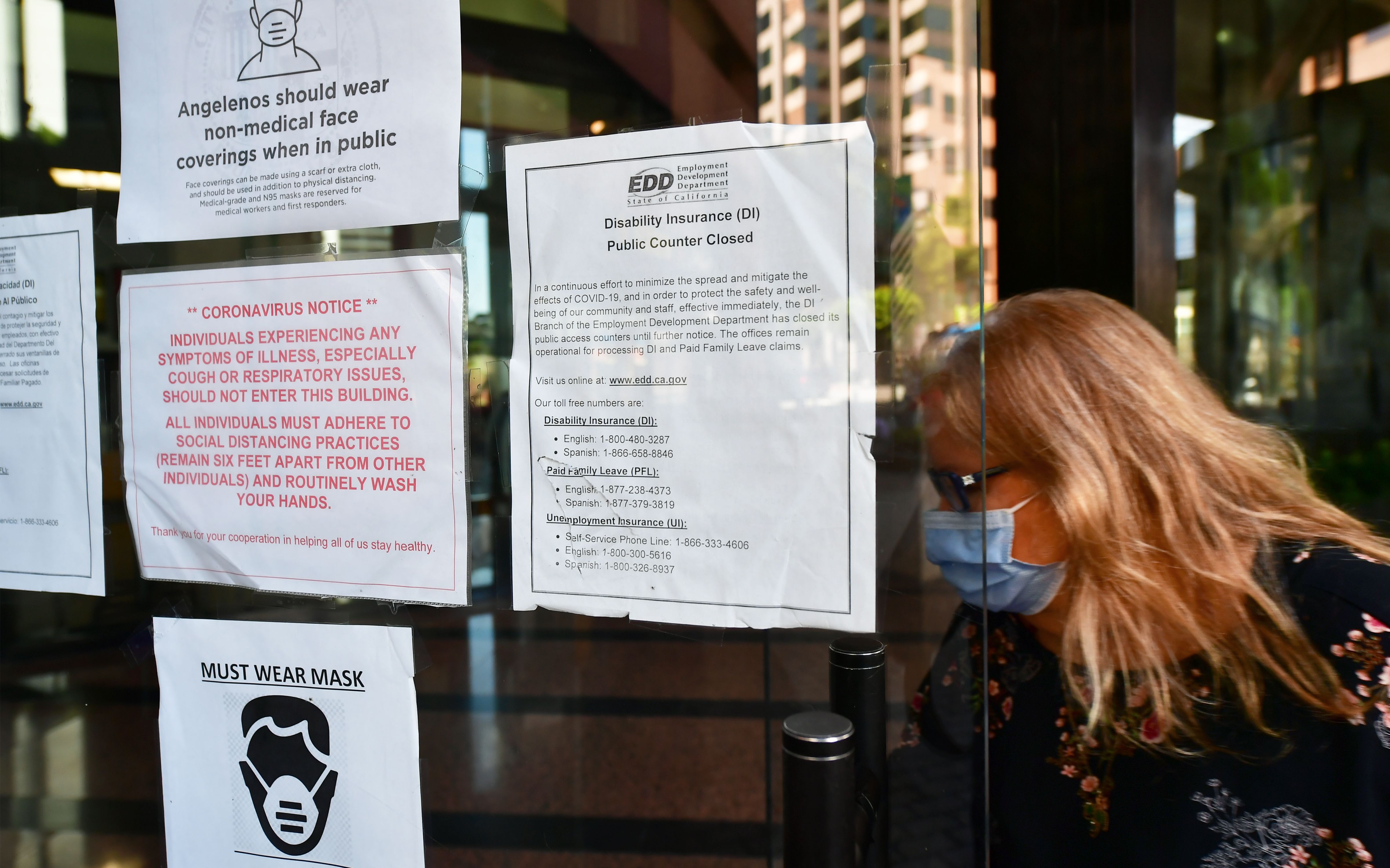 A woman wearing a facemask enters a building where the Employment Development Department has its offices in Los Angeles on May 4, 2020. (FREDERIC J. BROWN/AFP via Getty Images)