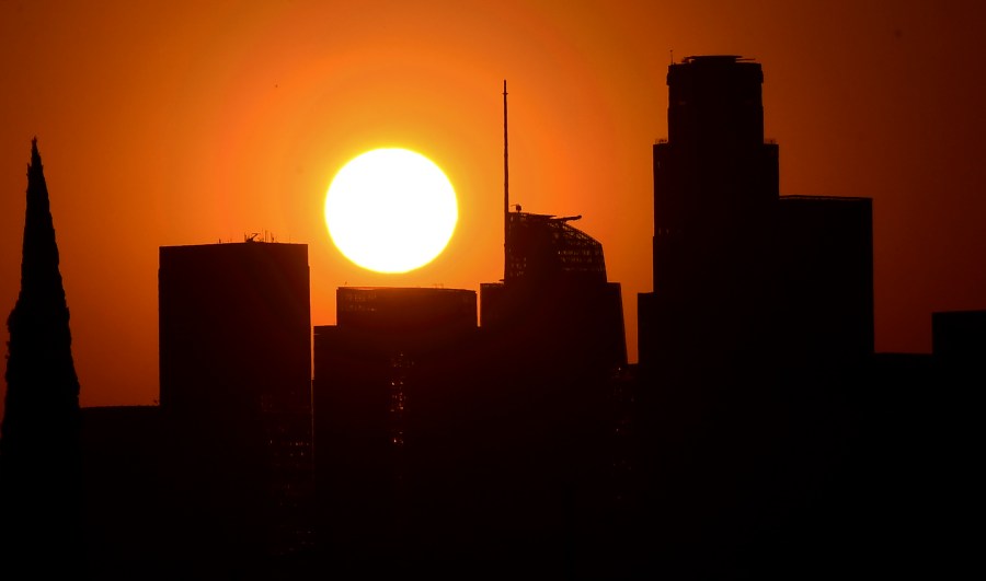 The sun sets behind highrise buildings in downtown Los Angeles on Sept. 30, 2020. (Frederic J. Brown / AFP / Getty Images)