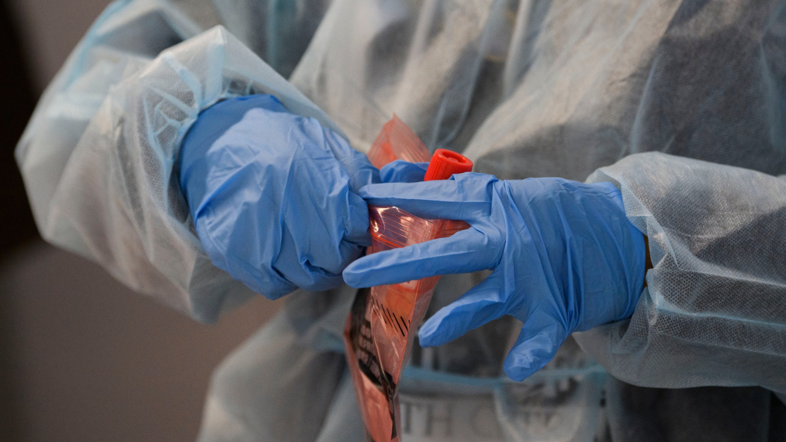 A healthcare worker places a Covid-19 nasal swab test for a traveler to Hawaii into a specimen bag during the Covid-19 pandemic at Los Angeles International Airport (LAX) in Los Angeles, California, November 18, 2020. (Patrick Fallon/AFP via Getty Images)