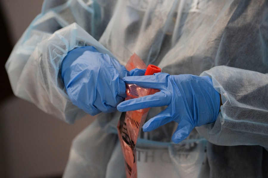 A healthcare worker places a Covid-19 nasal swab test for a traveler to Hawaii into a specimen bag during the Covid-19 pandemic at Los Angeles International Airport (LAX) in Los Angeles, California, November 18, 2020. (Patrick Fallon/AFP via Getty Images)