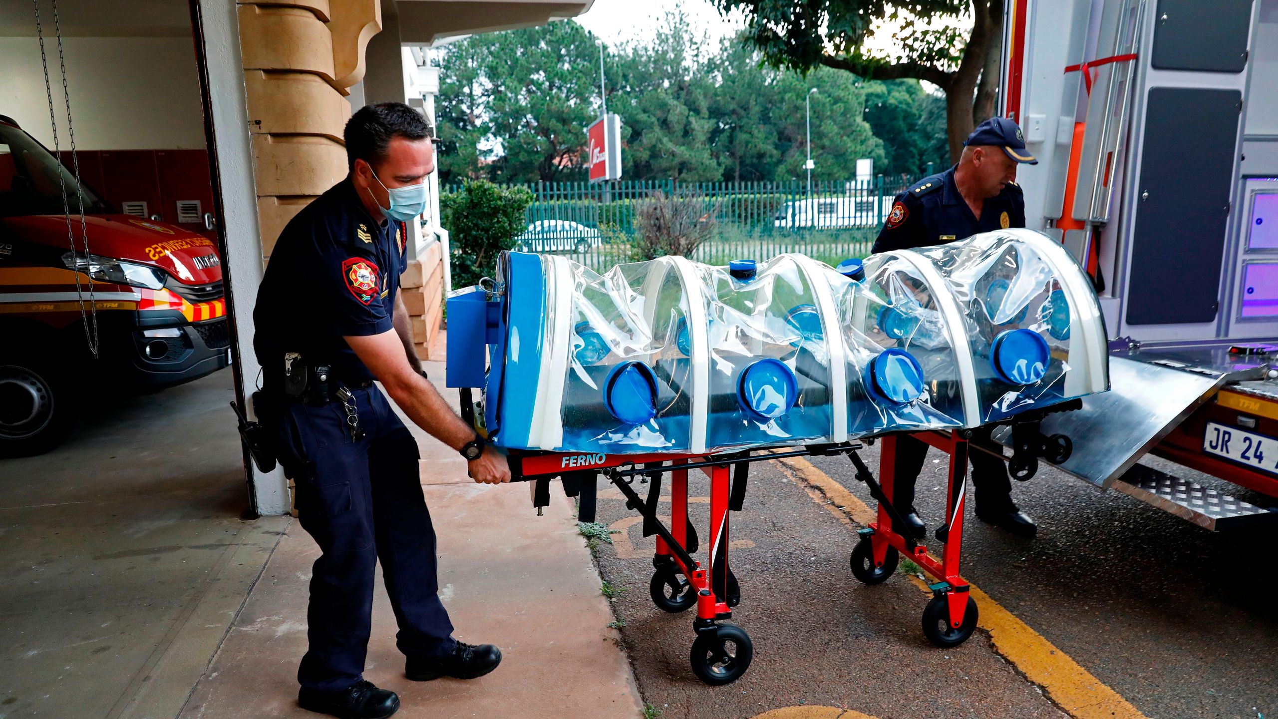 City of Tshwane's Special Infection Unit Leading Emergency Care practitioners push the isolation chamber equipped with a negative pressure filtration system used to transport positive COVID-19 patients before starting their night shift at the Hatfield Emergency Station, in Pretoria, on Dec. 28, 2020. ((PHILL MAGAKOE/AFP via Getty Images)