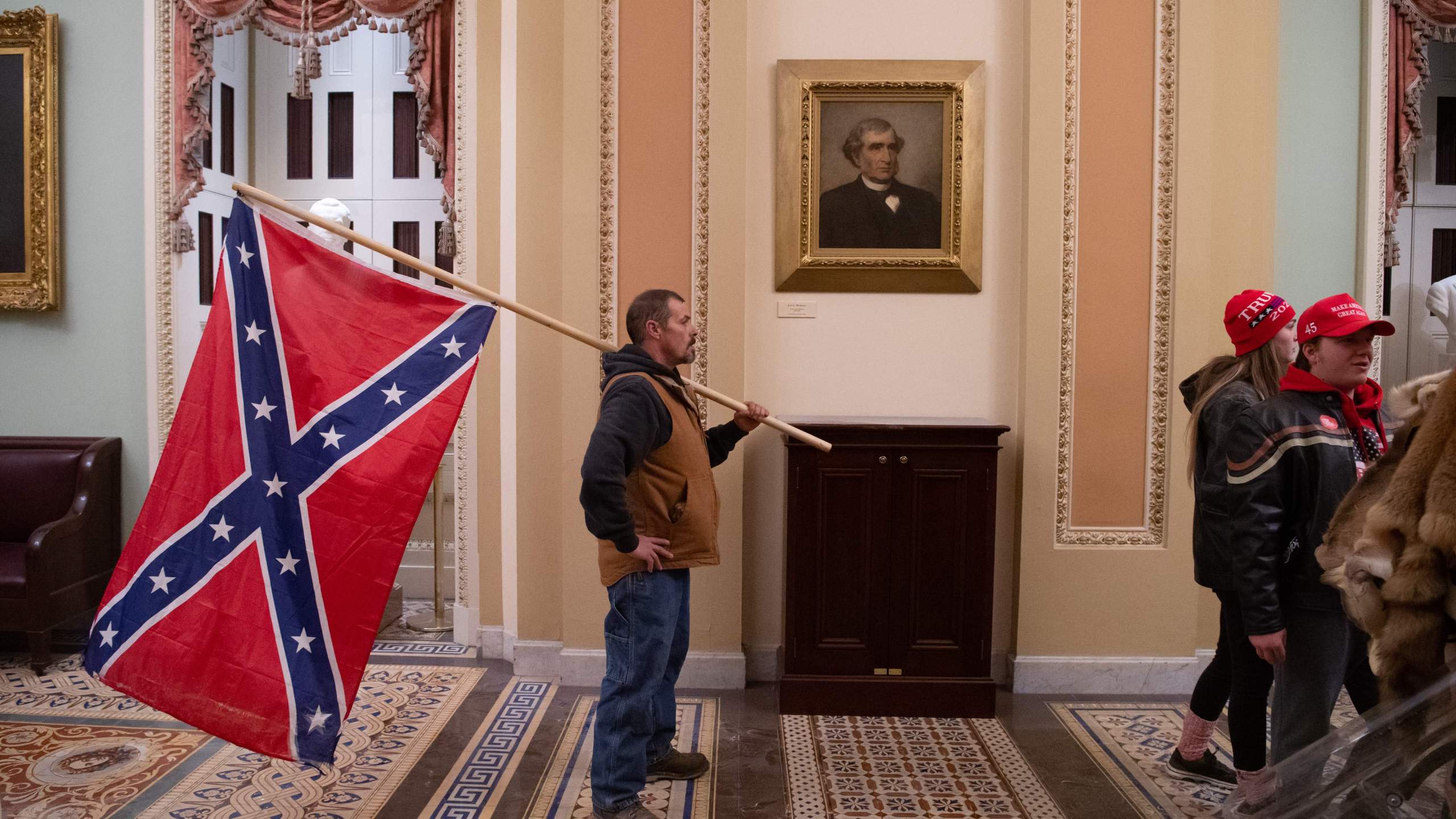 A supporter of Donald Trump holds a Confederate flag outside the Senate Chamber during a protest after breaching the US Capitol in Washington, D.C., Jan. 6, 2021. (SAUL LOEB/AFP via Getty Images)