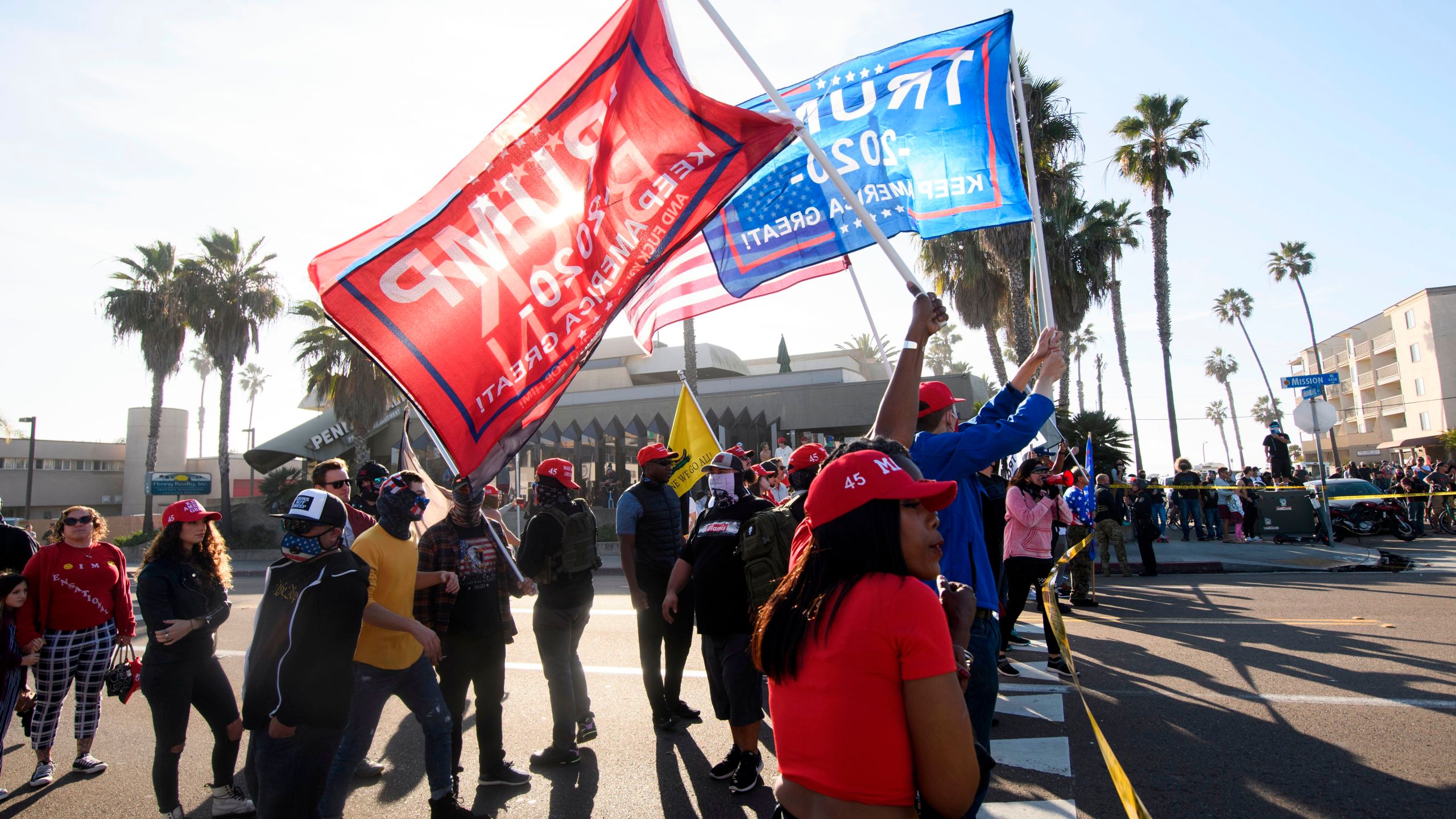 People hold flags during a "Patriot March" demonstration in support of Donald Trump, separated from counter-protesters by a police skirmish line on Jan. 9, 2021 in the Pacific Beach neighborhood of San Diego. (PATRICK T. FALLON/AFP via Getty Images)