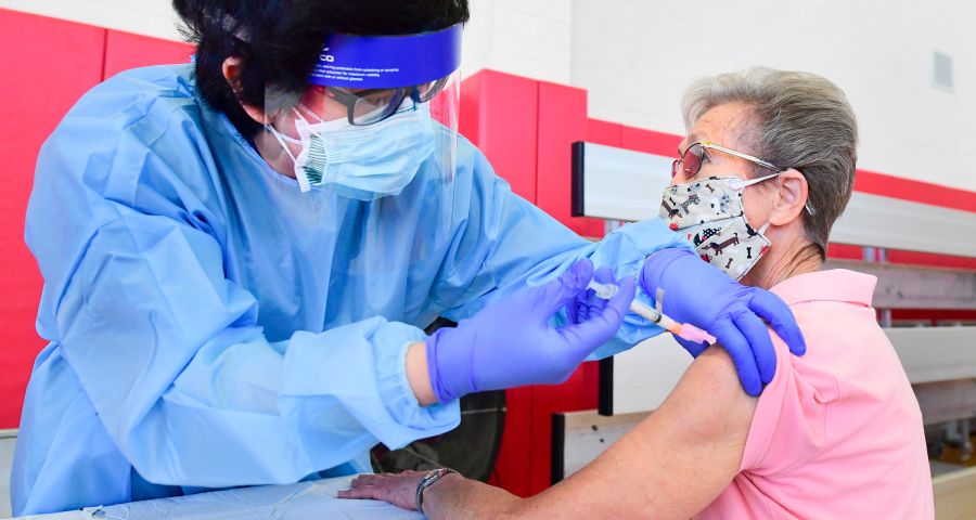 Registered nurse Kevin Salgado administers the COVID-19 vaccine into the arm of Arline Allman, 86, at the Corona High School gymnasium in Corona in Riverside County, on Jan. 15, 202. (FREDERIC J. BROWN/AFP via Getty Images)