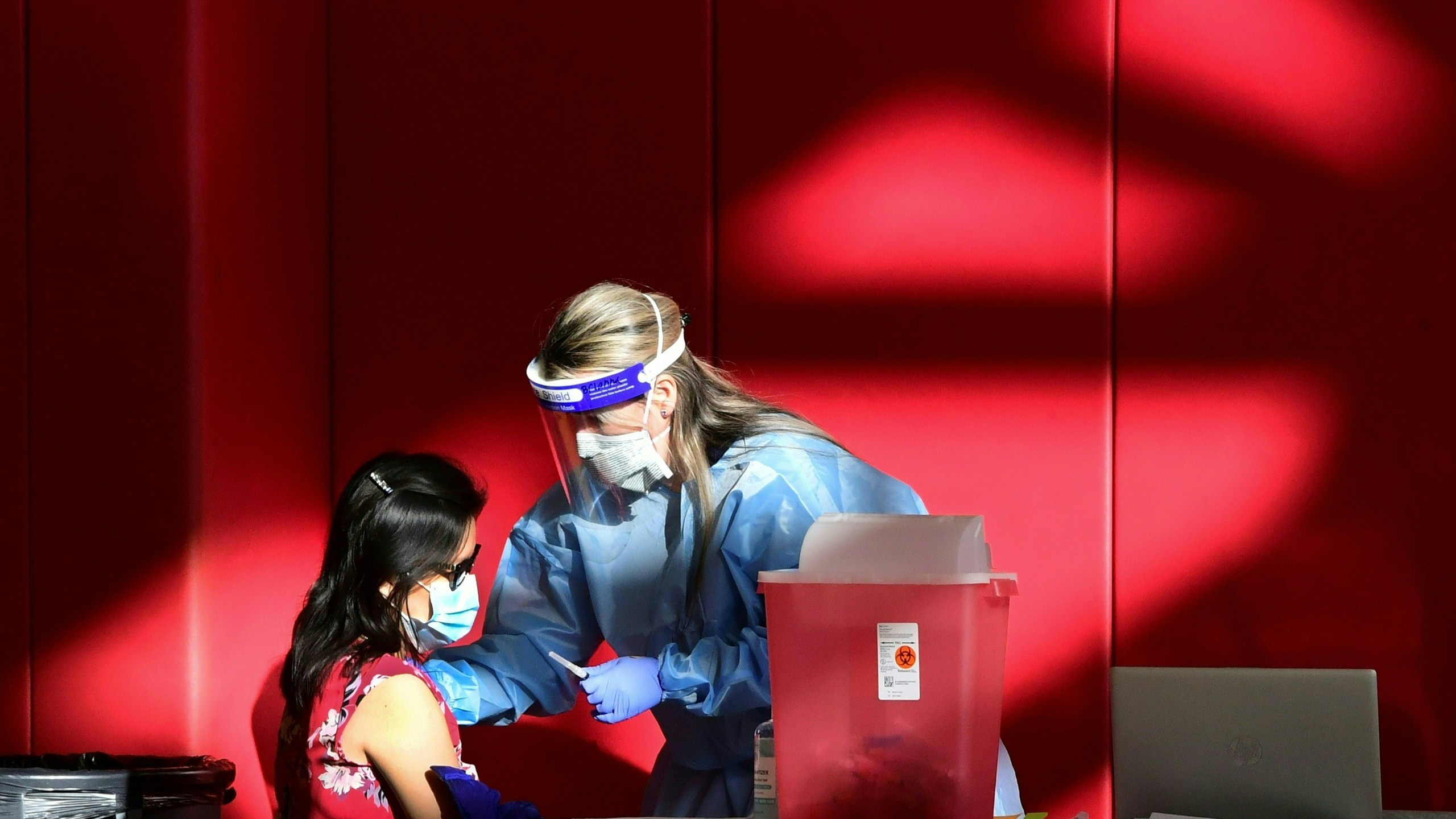 A registered nurse administers the COVID-19 vaccine into the arm of a woman at the Corona High School gymnasium in the Riverside County city of Corona, California on January 15, 2021, a day after California began offering the coronavirus vaccine to residents 65 and older. (FREDERIC J. BROWN/AFP via Getty Images)