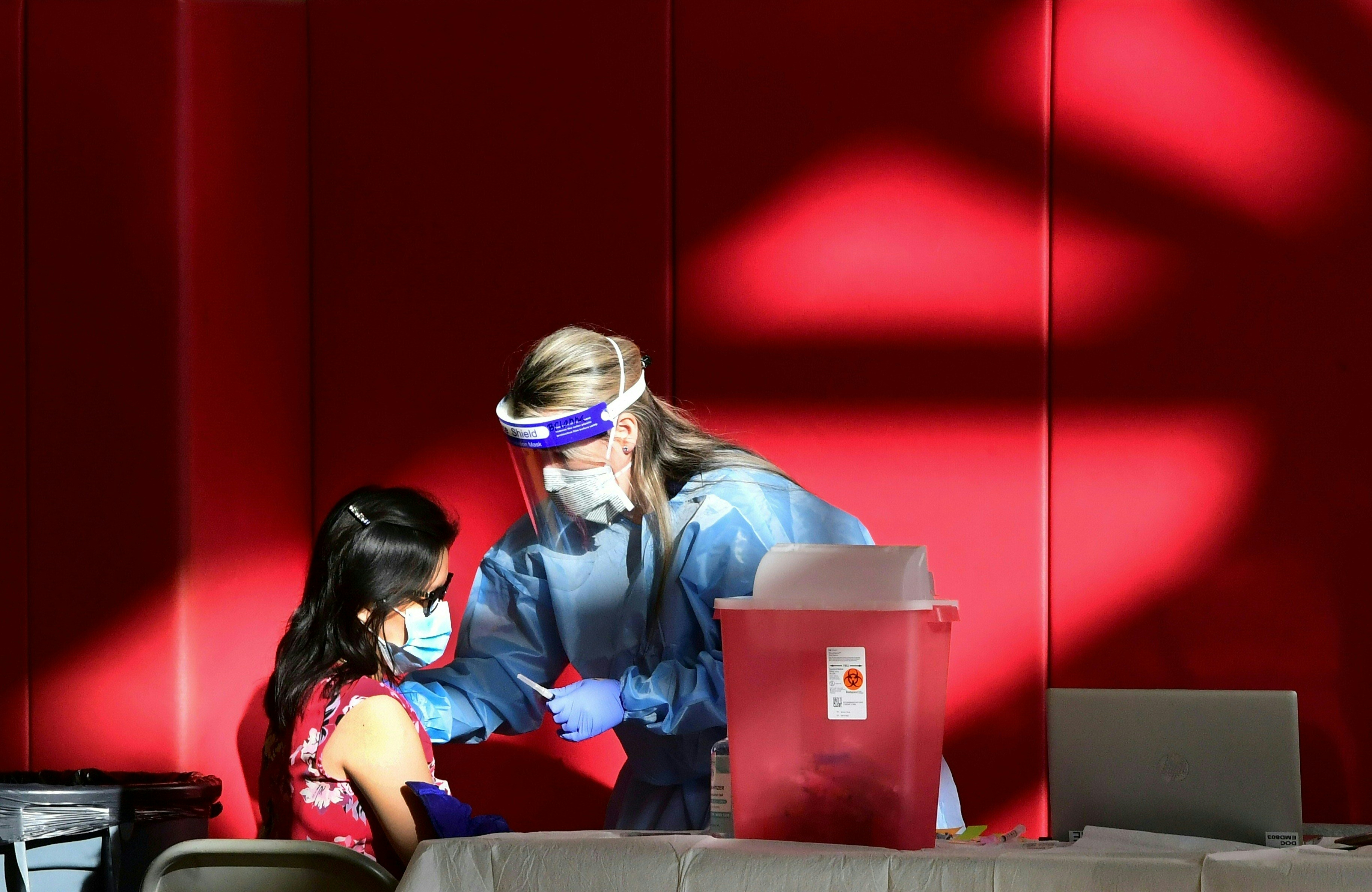 A registered nurse administers the COVID-19 vaccine into the arm of a woman at the Corona High School gymnasium in the Riverside County city of Corona, California on January 15, 2021, a day after California began offering the coronavirus vaccine to residents 65 and older. (FREDERIC J. BROWN/AFP via Getty Images)