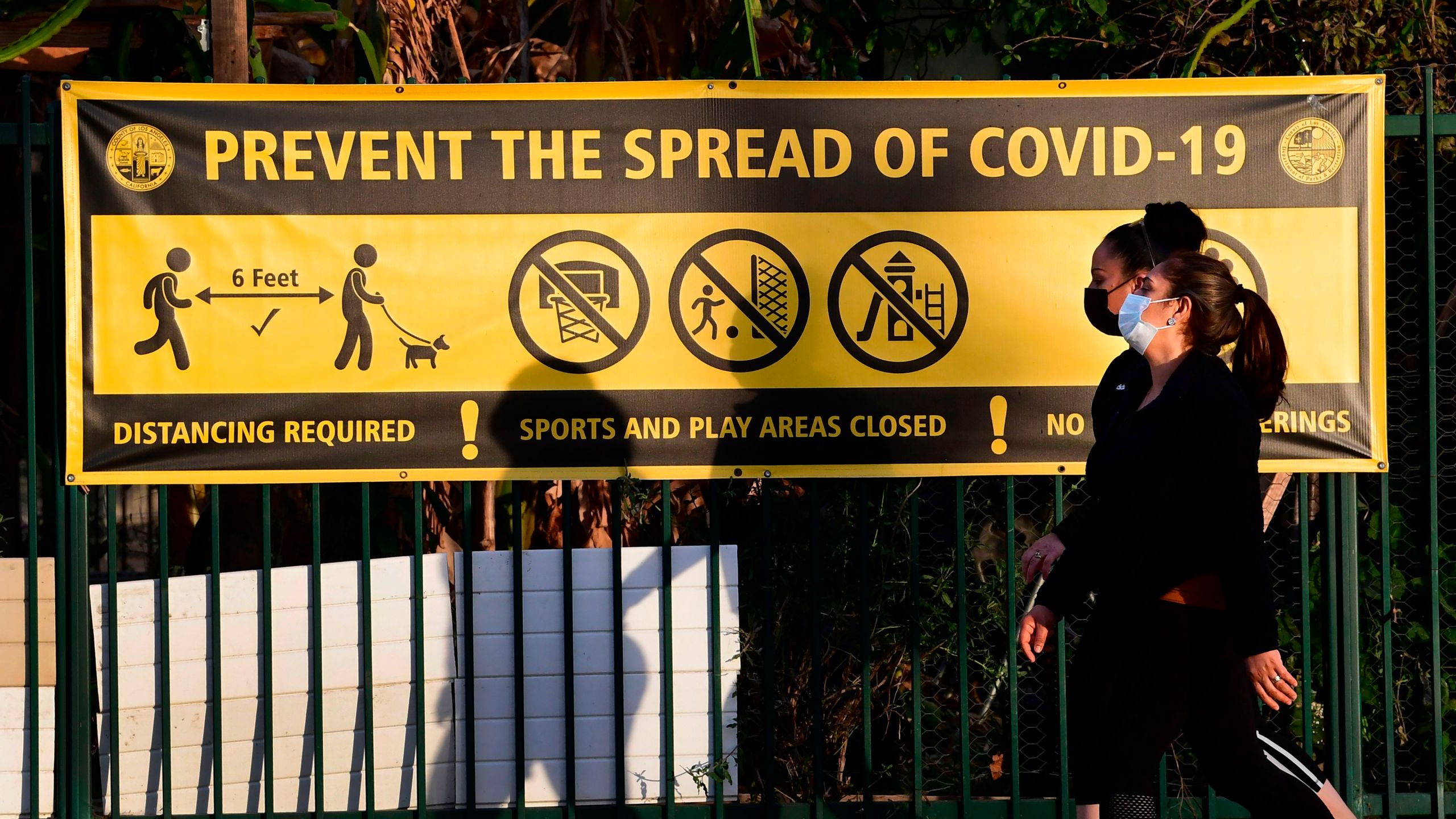 Pedestrians wearing facemasks walk past a prevent the spread of Covid-19 banner in Los Angeles, California on January 19, 2020. (Frederic J. Brown/AFP via Getty Images)