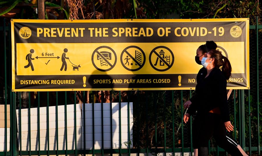 Pedestrians wearing facemasks walk past a prevent the spread of Covid-19 banner in Los Angeles, California on January 19, 2020. (Frederic J. Brown/AFP via Getty Images)