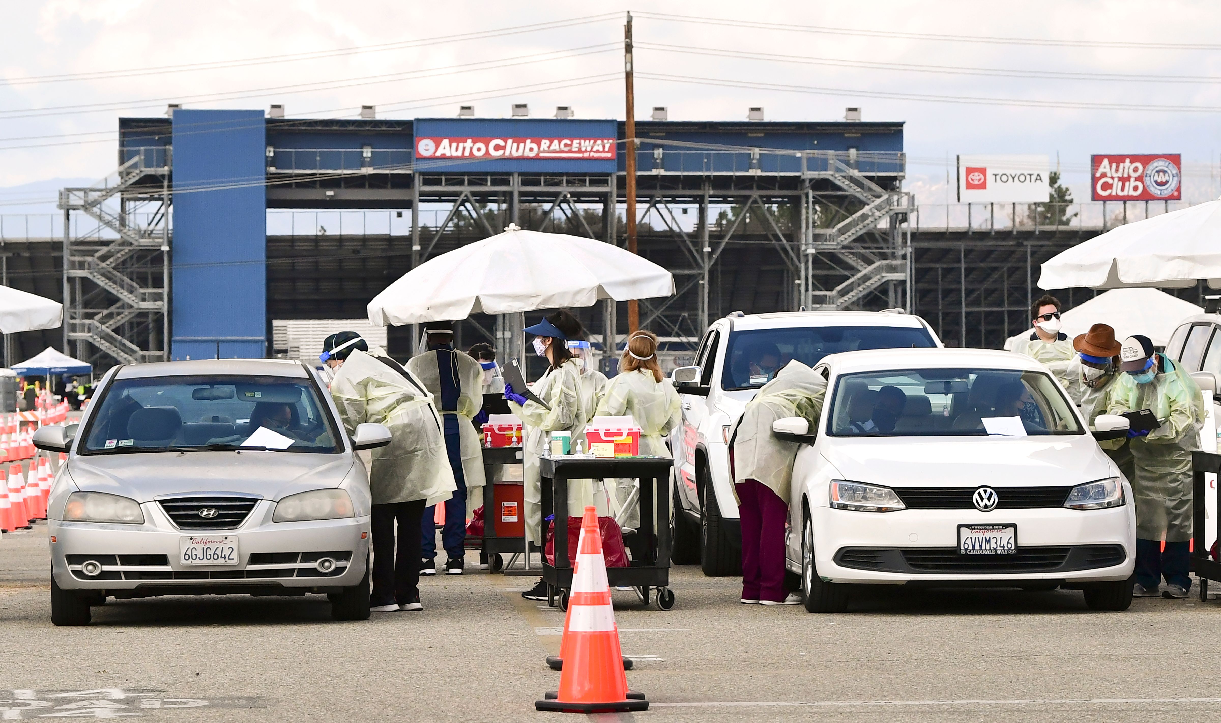 Health care personel dressed in personal protective gear help inoculate people arriving to receive COVID-19 vaccines at the Fairplex in Pomona on Jan. 22, 2021. (Frederic J. Brown / AFP / Getty Images)