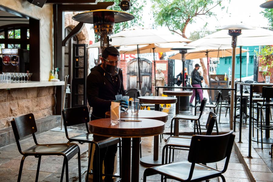 An employee sanitizes the tables of The Abbey Food & Bar outdoor seating area on January 29, 2021 in West Hollywood, California. (VALERIE MACON/AFP via Getty Images)