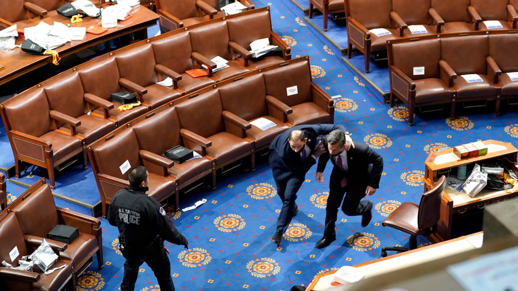 Members of congress run for cover as protesters try to enter the House chamber during a joint session on Jan. 6, 2021. (Drew Angerer/Getty Images)