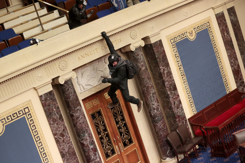 A protester is seen hanging from the balcony in the U.S. Senate Chamber on Jan. 6, 2021. (Win McNamee / Getty Images)