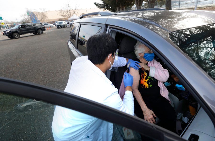 Safeway pharmacist Preston Young (L) administers a Moderna COVID-19 vaccination to Cecile Lusby (R) during a drive-thru vaccination clinic at the Sonoma County Fairgrounds on Jan. 13, 2021 in Santa Rosa, California. (Justin Sullivan/Getty Images)