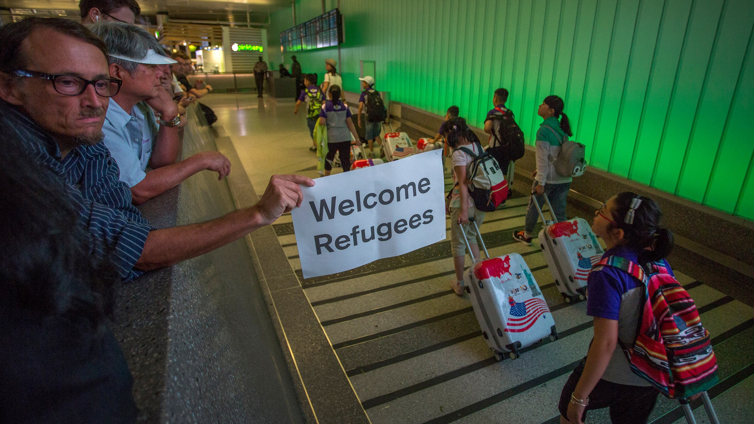 This file photo from June 29, 2017 shows a man carrying a welcome sign as international travelers arrive at LAX on the first day of the the partial reinstatement of the Trump travel ban, temporarily barring travelers from six Muslim-majority nations from entering the U.S. (David McNew/Getty Images)