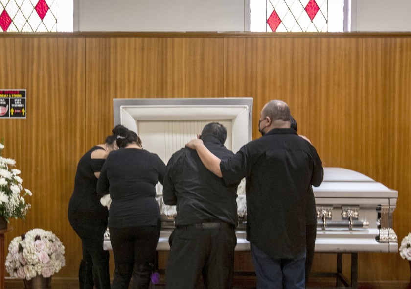 Family members mourn Edith Fernandez alongside her casket Dec. 20 at the Continental Funeral Home in East Los Angeles. The 47-year-old died Dec. 8 from complications of COVID-19.(Brian van der Brug / Los Angeles Times)