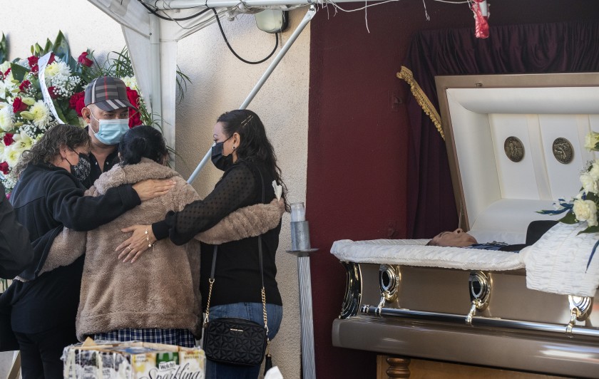 Family and friends console one another as they gather at a service Dec. 20 for Julio Aguilar at the Continental Funeral Home in East Los Angeles. The 74-year-old died Nov. 28 from complications of COVID-19. (Brian van der Brug/Los Angeles Times)