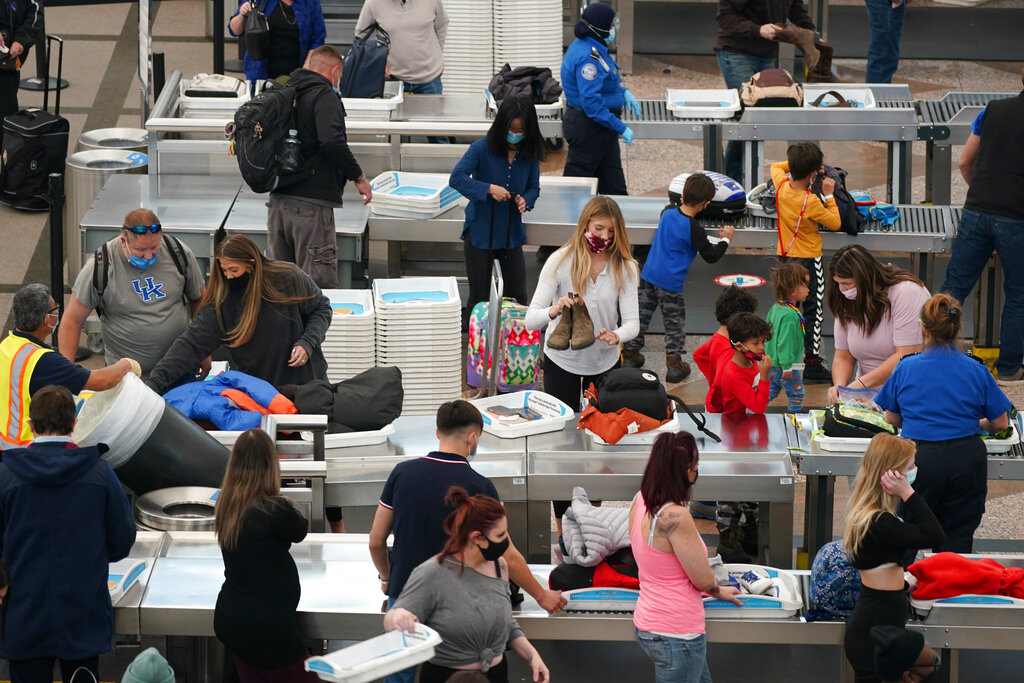 Travelers wear face masks while passing through the south security checkpoint in the main terminal of Denver International Airport Tuesday, Dec. 22, 2020, in Denver. (AP Photo/David Zalubowski)