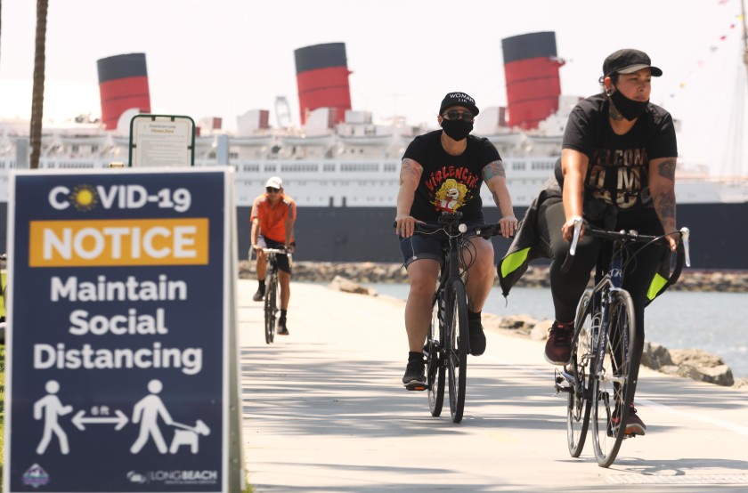 With the Queen Mary in the background, cyclists in Long Beach make their way along a bike path in May 2020. The company that operates the former ocean liner filed for bankruptcy protection. (Genaro Molina / Los Angeles Times)