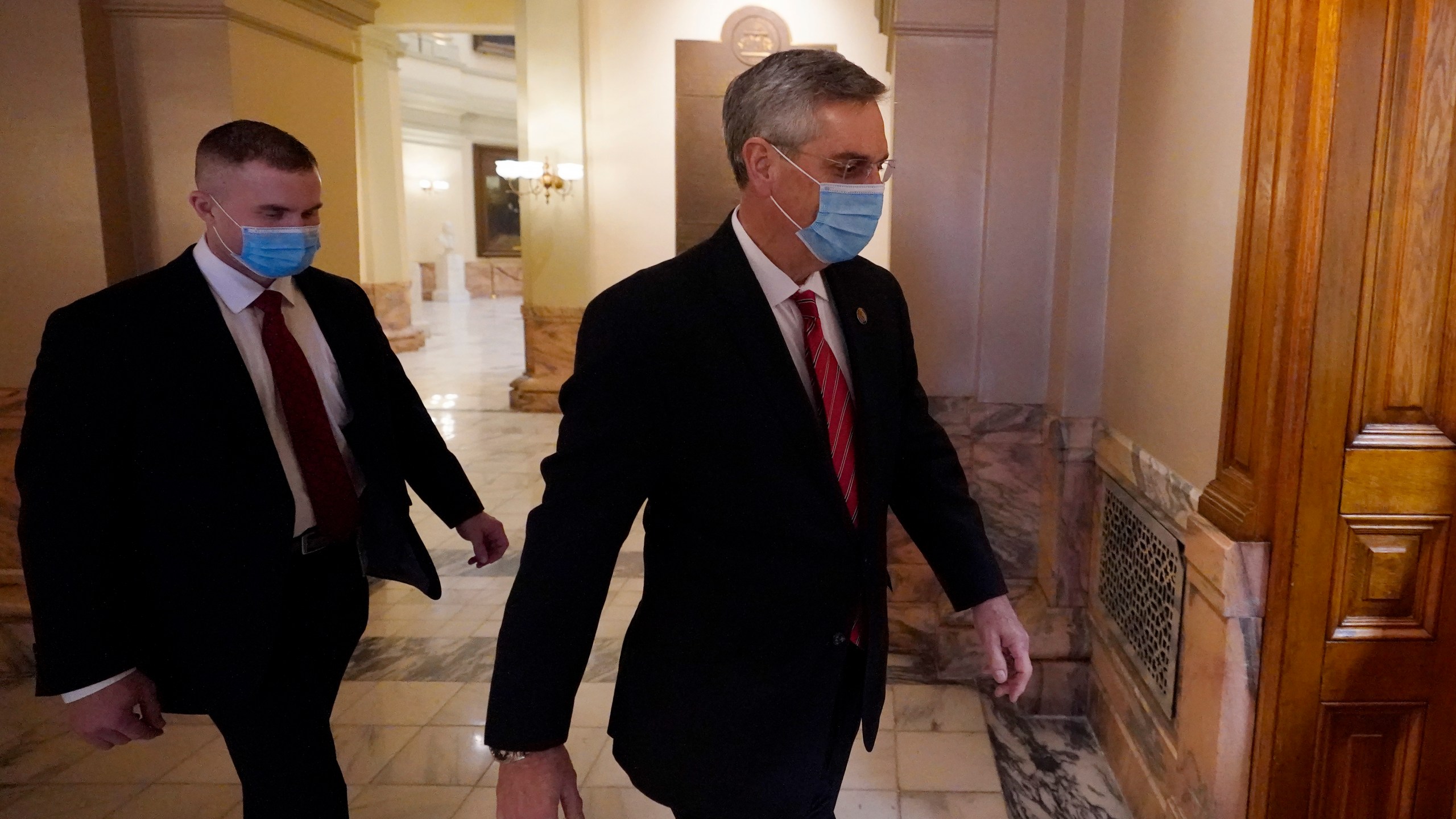 Georgia Secretary of State Brad Raffensperger, right, walks to his office in the Capitol Building Monday, Jan. 4, 2021, in Atlanta. (AP Photo/John Bazemore)