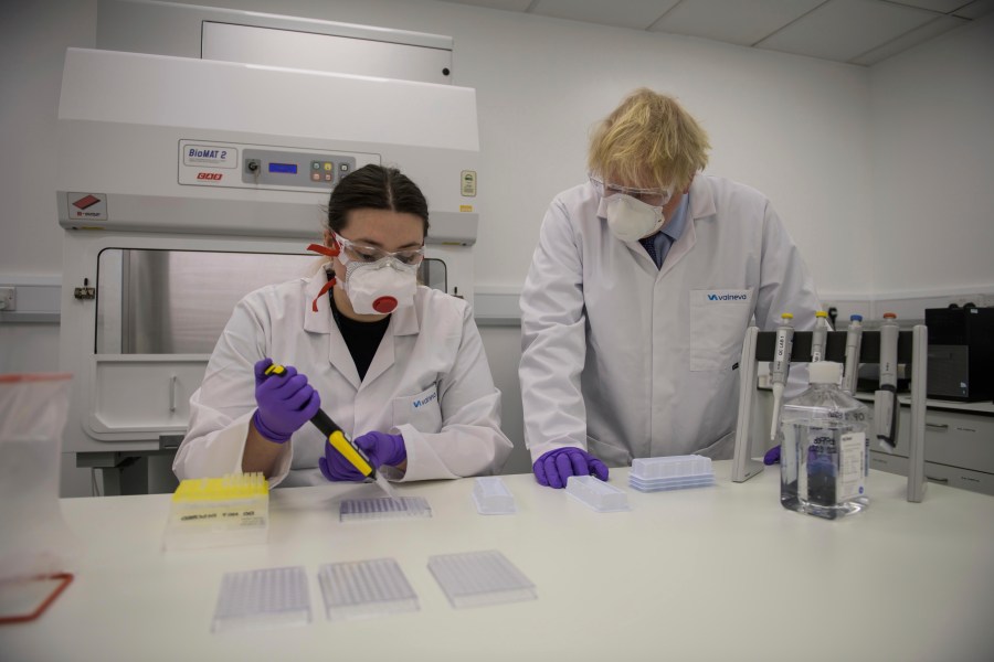 Britain's Prime Minister Boris Johnson with quality control technician Kerri Symington, visits the French biotechnology laboratory Valneva in Livingston, Scotland, Thursday Jan. 28, 2021, where they will be producing a COVID-19 vaccine on a large scale, during a visit to Scotland. (Wattie Cheung/Pool via AP)