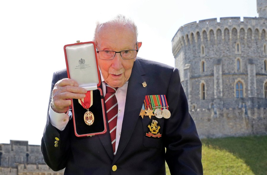 In this Friday, July 17, 2020 file photo, Captain Sir Thomas Moore poses for the media after receiving his knighthood from Britain's Queen Elizabeth, during a ceremony at Windsor Castle in Windsor, England. Tom Moore, the 100-year-old World War II veteran who captivated the British public in the early days of the coronavirus pandemic with his fundraising efforts, has been admitted to a hospital with COVID-19, his daughter said Sunday Jan. 31, 2021. (Chris Jackson/Pool Photo via AP, File)