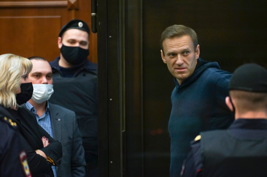 In this handout photo provided by Moscow City Court Russian opposition leader Alexei Navalny talks to his lawyers while standing in a cage during a hearing to a motion from the Russian prison service to convert the suspended sentence of Navalny from the 2014 criminal conviction into a real prison term in the Moscow City Court in Moscow on Feb. 2, 2021. (Moscow City Court via Associated Press)