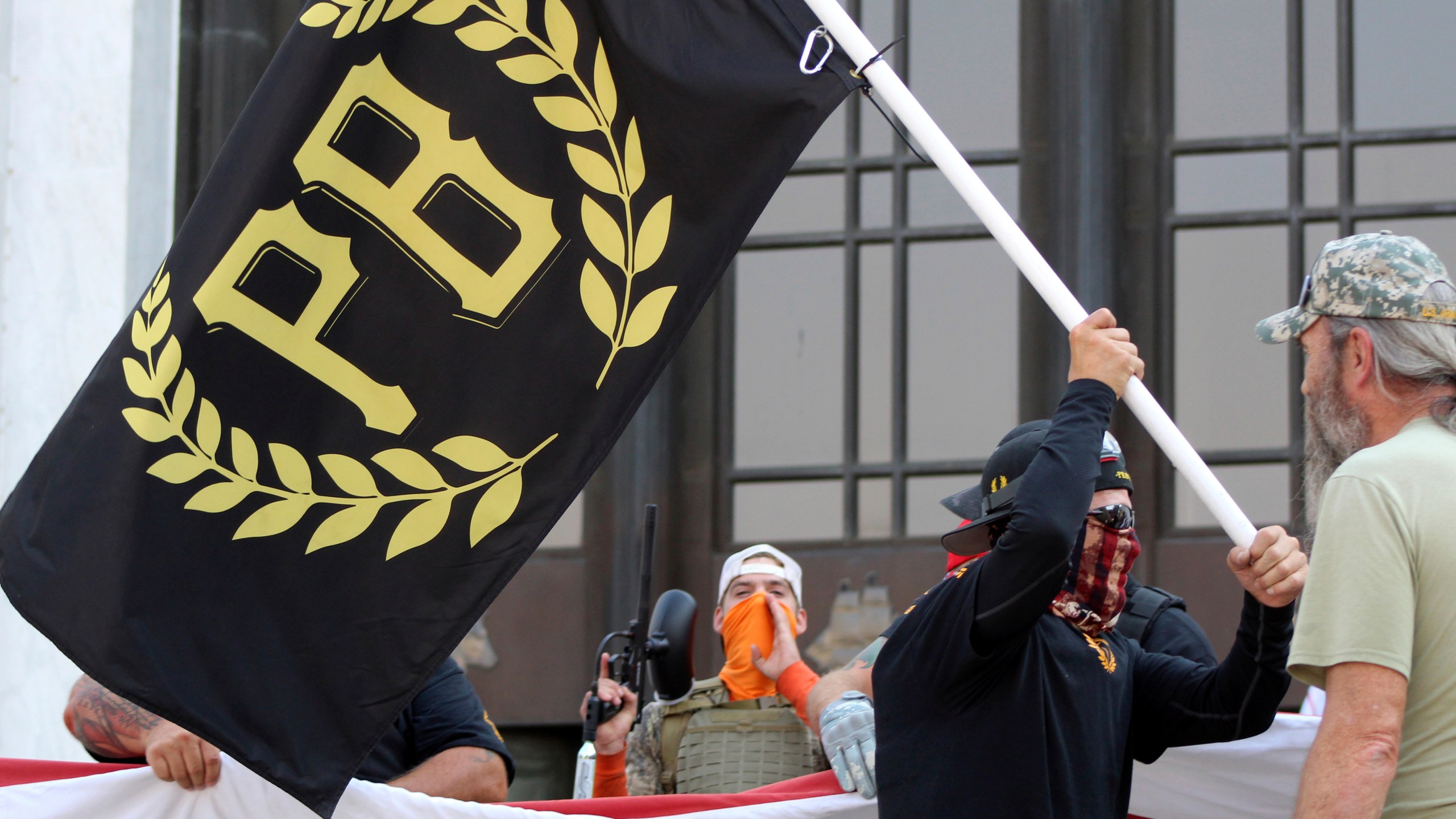 In this Sept. 7, 2020, file photo, a protester carries a Proud Boys banner, a right-wing group, while other members start to unfurl a large U.S. flag in front of the Oregon State Capitol in Salem, Ore. The Canadian government designated the Proud Boys group as a terrorist entity on Wednesday, Feb. 3, 2021, noting they played a pivotal role in the insurrection at the U.S. Capitol on Jan. 6. (AP Photo/Andrew Selsky, File)