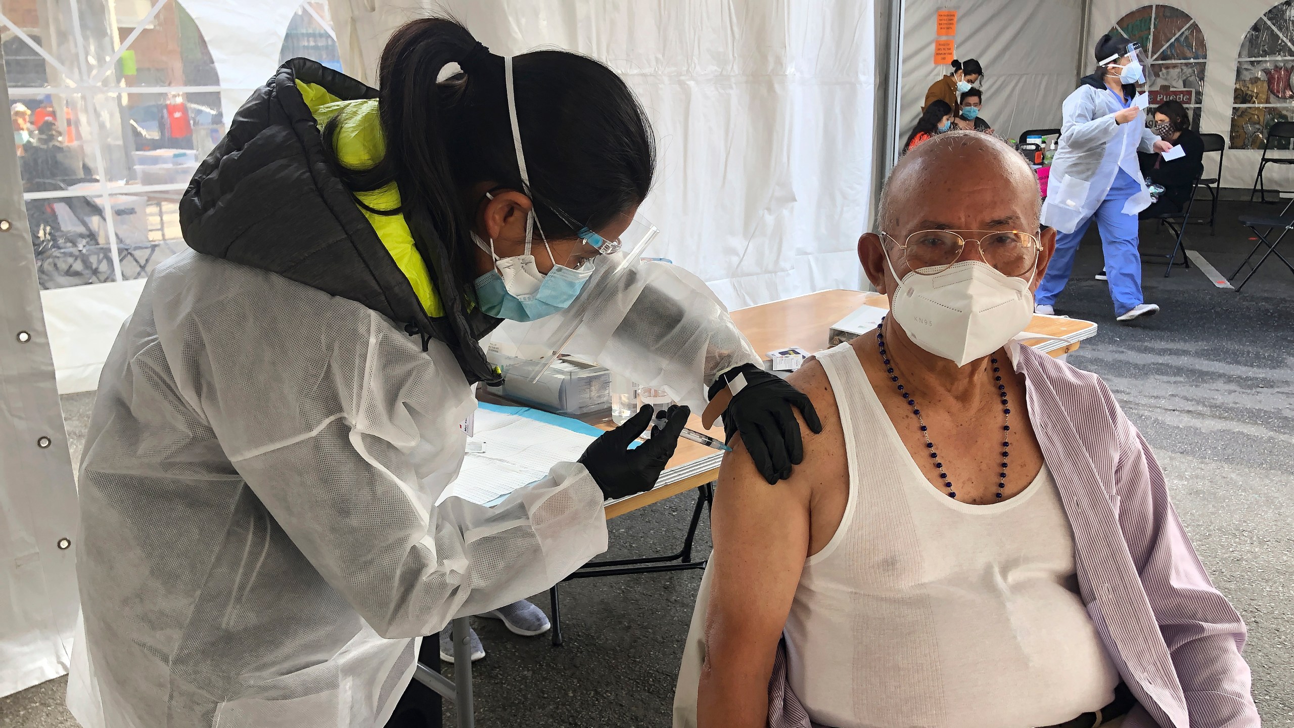 Victor Villegas, 78, right, receives a COVID-19 vaccine shot from a health care worker at a vaccination site in the Mission district of San Francisco, Monday, Feb. 8, 2021. (AP Photo/Haven Daley)